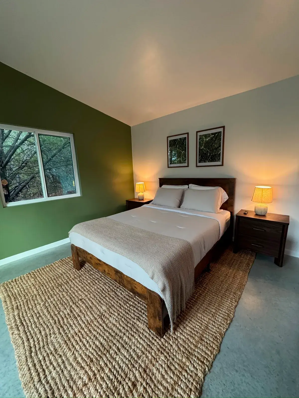 The queen bed against the green accent wall, with a lamp on each nightstand