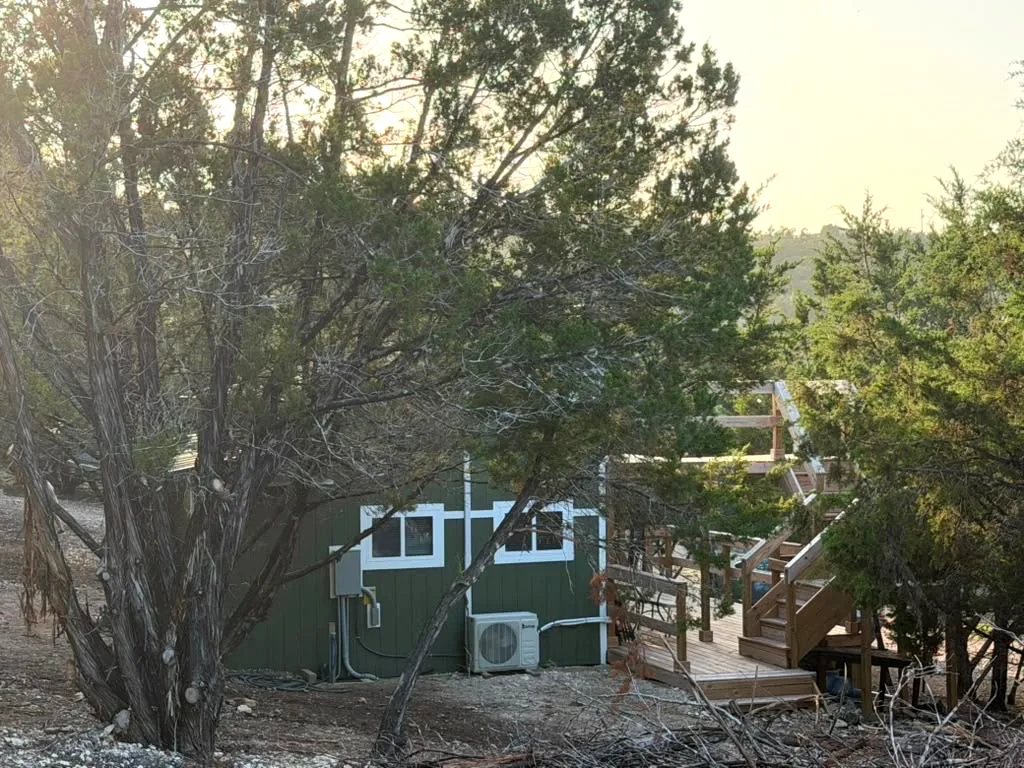 Casita 1 from the trees — olive-green siding, white trim and a raised deck
