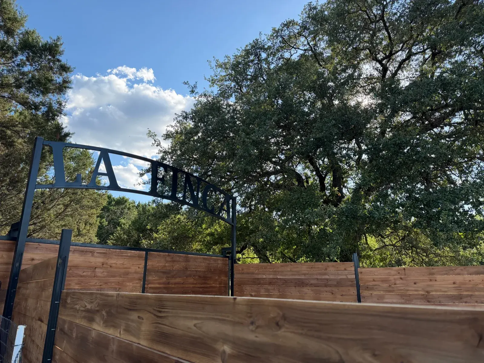 The La Finca entrance sign above a cedar fence, with the pasture beyond